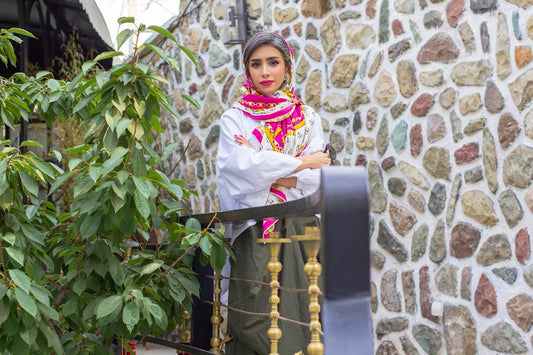 girl in white and red floral hijab standing beside green plant