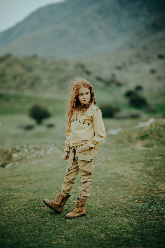 a little girl standing on top of a lush green field