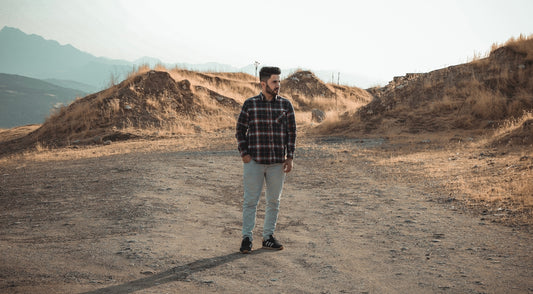 man standing in a field under white clouds during daytime
