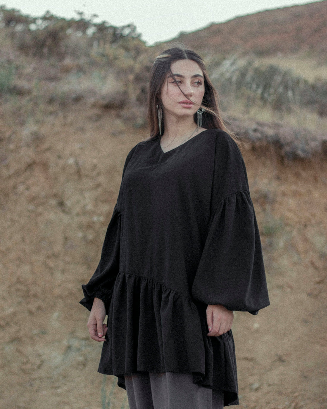 woman in black long sleeve dress standing on brown grass field during daytime