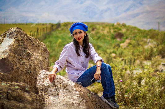 woman in white and gray striped long sleeve shirt and blue denim jeans sitting on brown