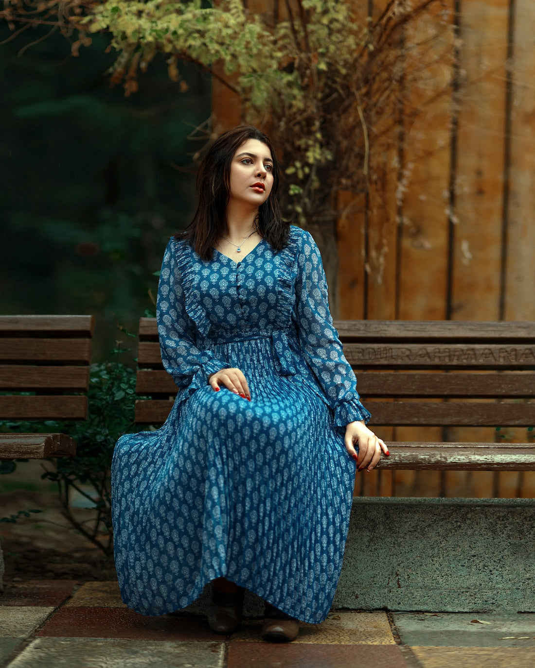 a woman in a blue dress sitting on a bench