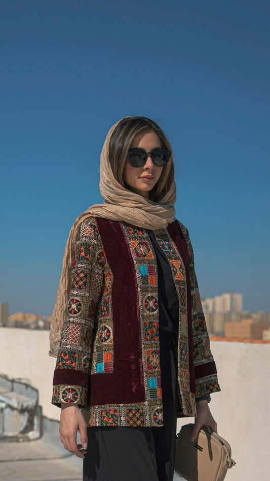 a woman wearing a scarf and sunglasses holding a purse