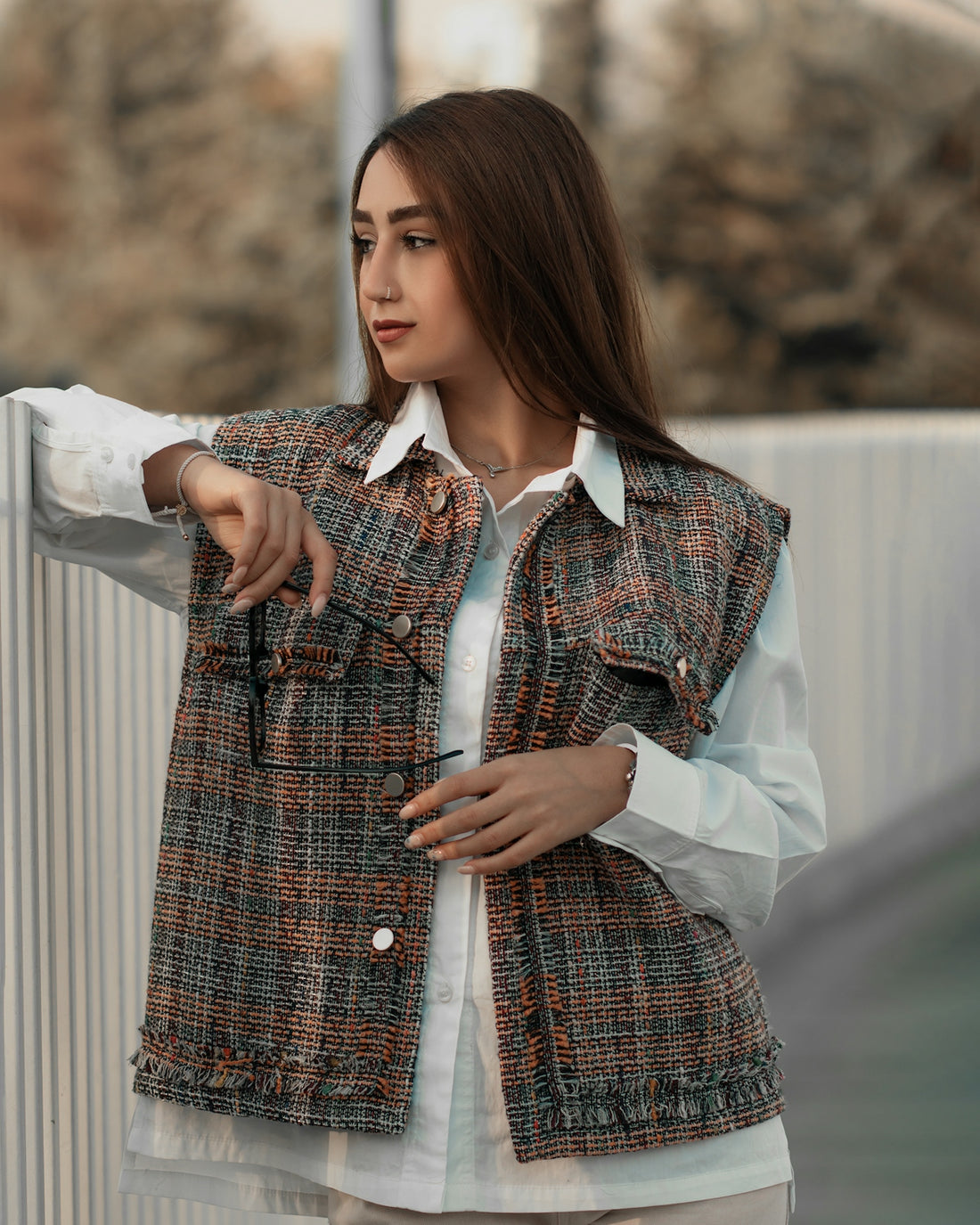 a woman pointing at something while standing next to a fence